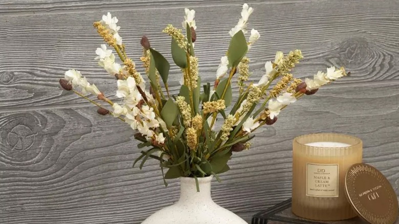 Cream Flower and Berry Picks from Hobby Lobby are arranged in a cream vase next to a scented candle