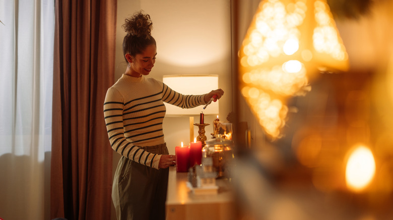 A woman lights candles in a cozy room