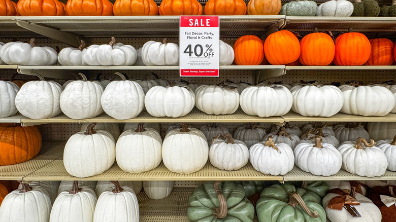 A 40% Off Fall Decor, Party, Floral & Crafts sign hangs in front of pumpkin decor on the shelves of a Hobby Lobby store