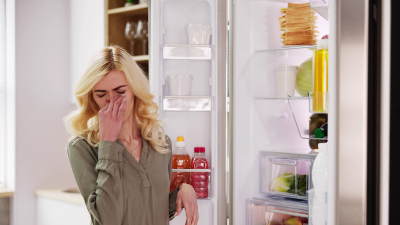 A woman recoiling from a smelly fridge