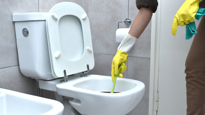 A person wearing gloves cleaning a toilet