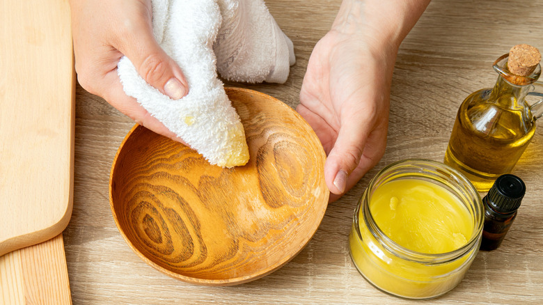 Wiping oil wood polish over wooden bowl