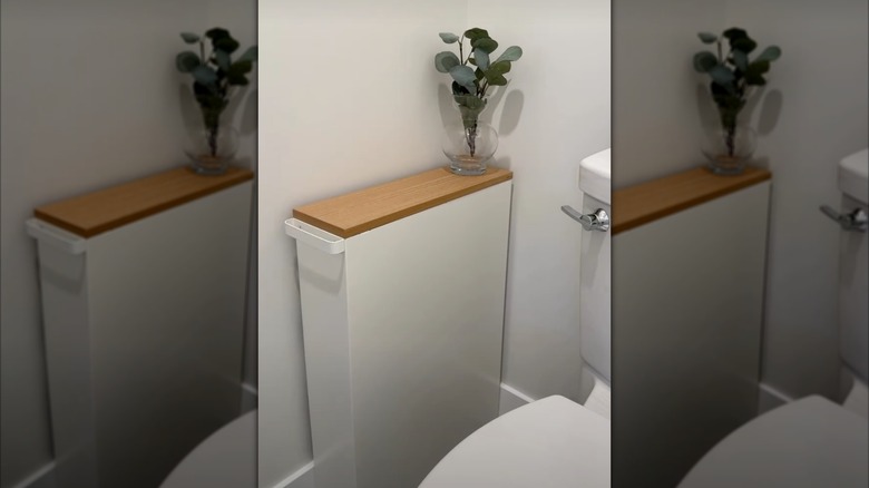 Narrow covered utility cart next to toilet