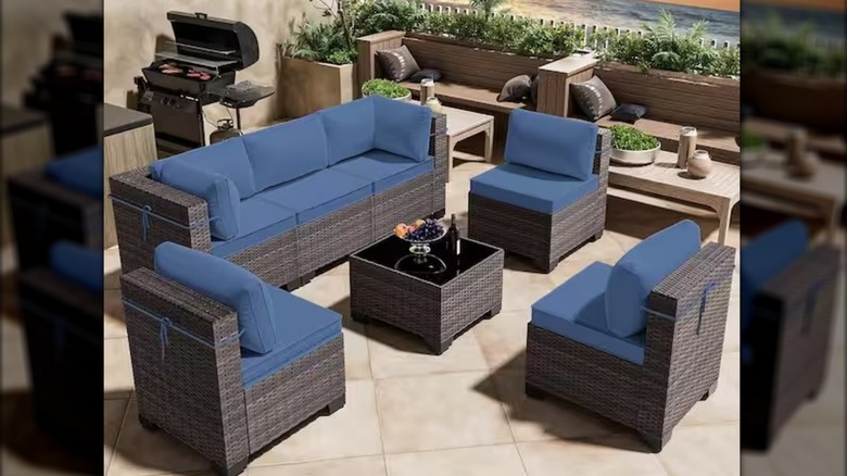 Seven-piece wicker outdoor set with navy blue cushions on a stone patio