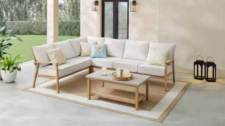 Beige cushioned outdoor sectional on an outdoor rug on a covered patio