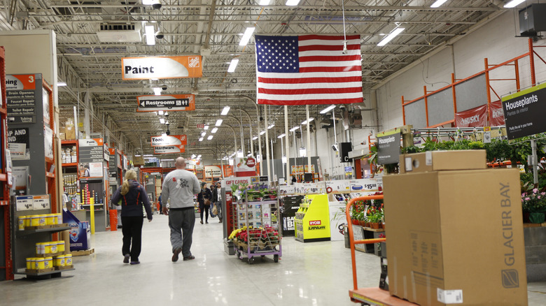two customers walking around in a Home Depot store with an American flag hanging overhead