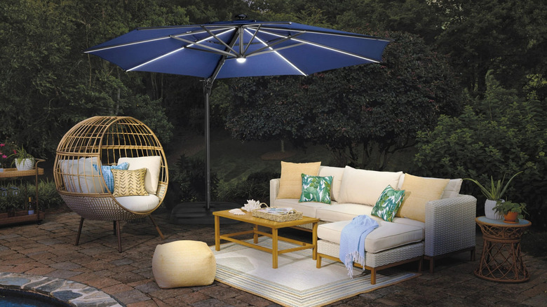 Cantilever umbrella on a patio next to a seating area at night with the lights turned on