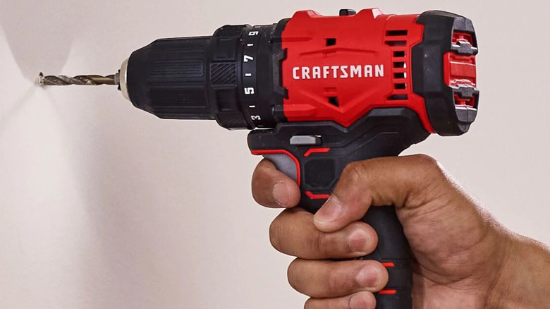 Person using a red Craftsman drill on a wall