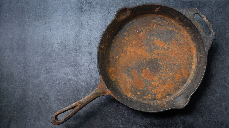 Black cast iron pan covered in rust
