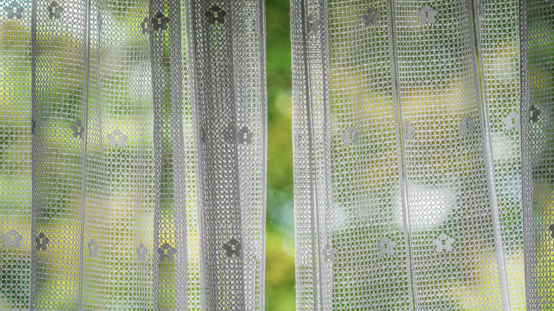White lace curtains hanging on a window