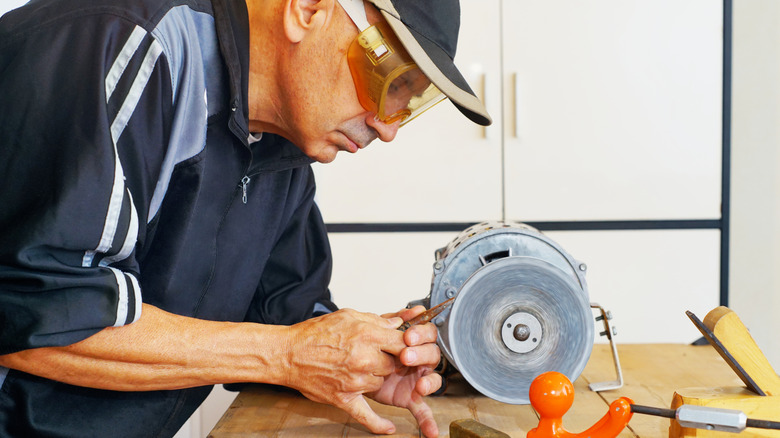 Man sharpening a tool on a bench grinder