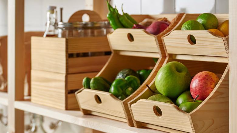 Fresh vegetables and fruit sit on a shelf inside a wooden CHOKLADHAJ food storage box from IKEA
