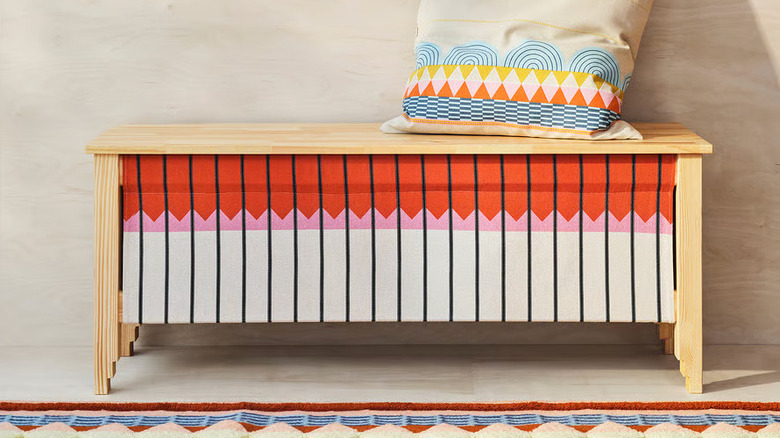 A colorful pillow sits on an OMMJÄNGE Bench with storage from IKEA