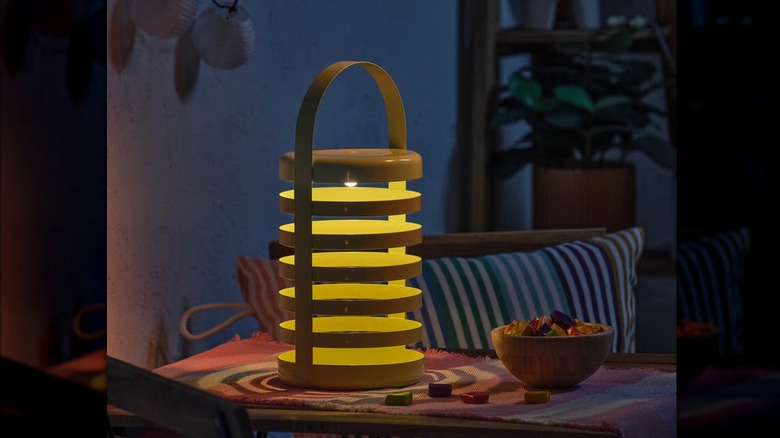 A modern green LED light sits on a patio table at dusk