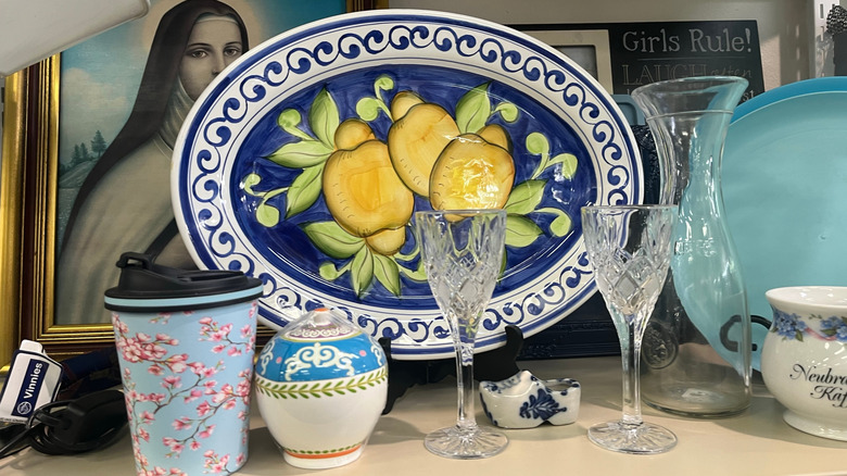 A serving platter in a thrift store next to glassware