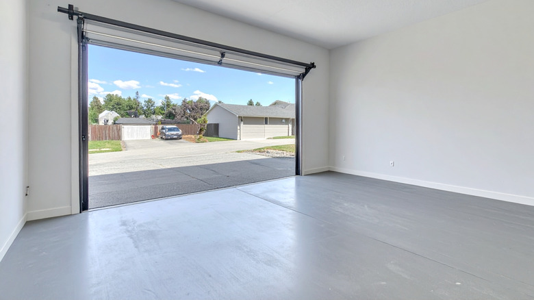 An empty garage with clear floors, door open to the neighborhood on a sunny day