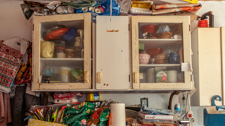 Cabinets in a messy kitchen full of disorganized items