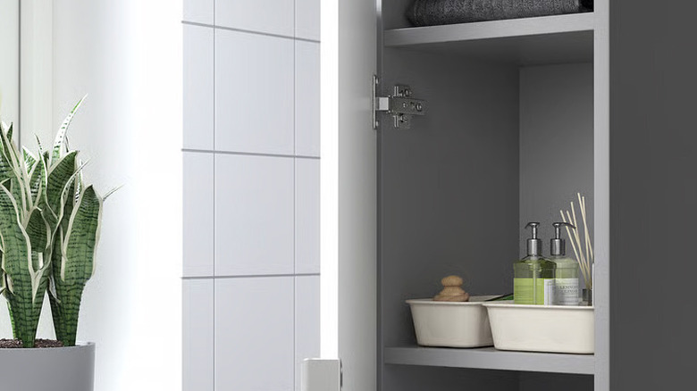 Two beige plastic NOJIG boxes holding toiletries sit on a shelf in a gray bathroom
