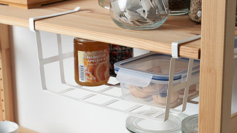 A white wire storage basket hangs on a wooden shelf