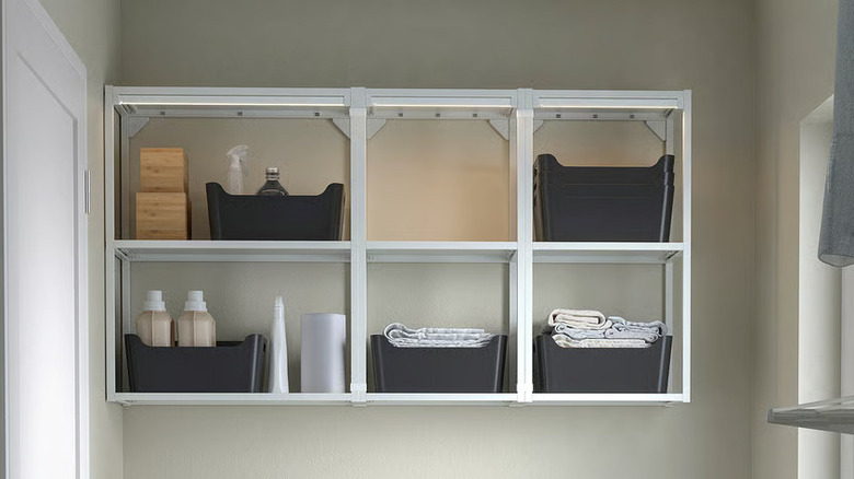 Several anthracite-colored UPPDATERA boxes sit inside wall-mounted cubbies in a laundry room