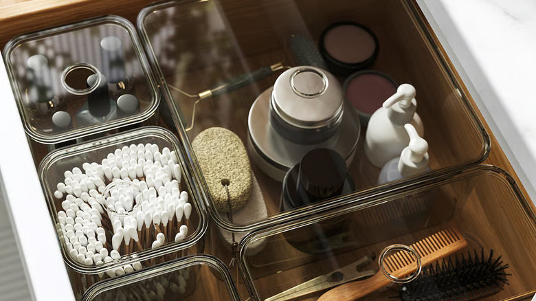 A translucent set of gray VISSLAÅN boxes is filled with bathroom toiletries