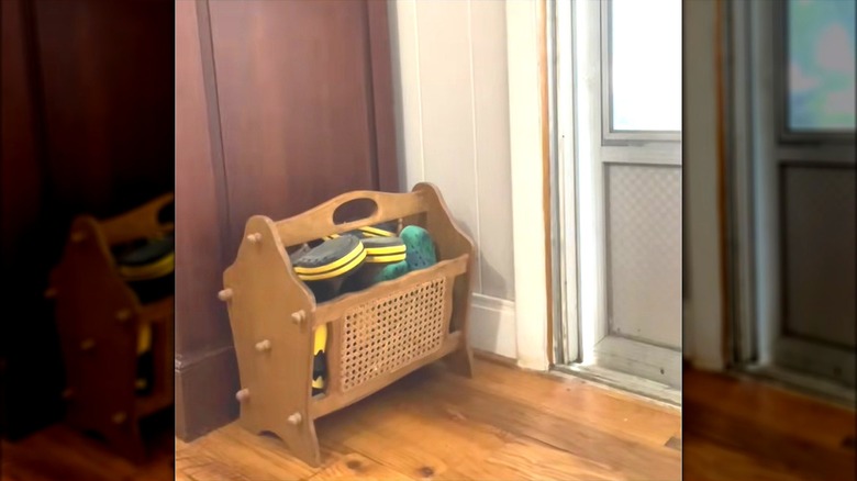 Outdoor shoes tucked in vintage wood rack by entryway door