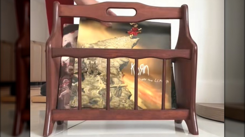 Woman tucking classic rock vinyl records into red-toned wood holder