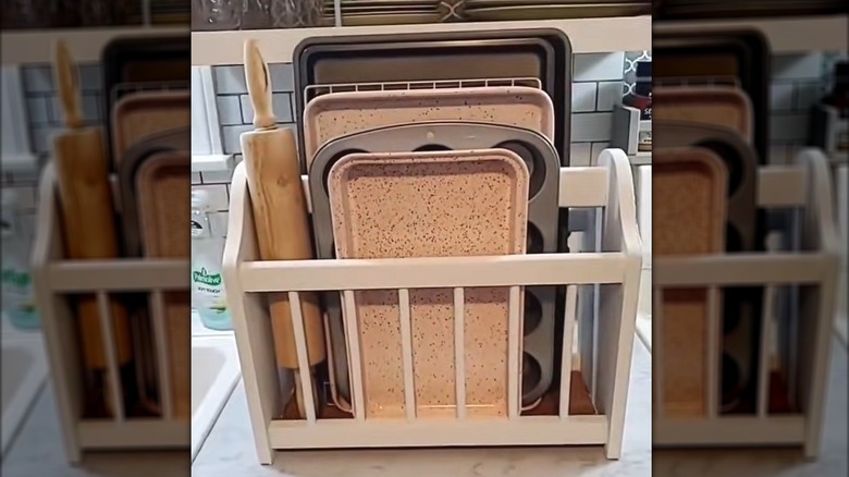 Assorted stylish cooking trays and rolling pin in a white magazine rack