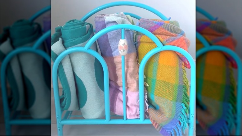 Rolled-up fleece blankets tucked in a painted blue magazine holder