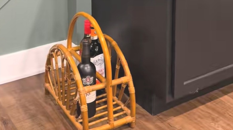 Dark wine bottles standing up on rustic bamboo magazine rack