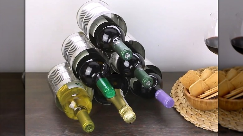 Pyramid wine bottle holder made of soup cans beside wine glass and snack setup