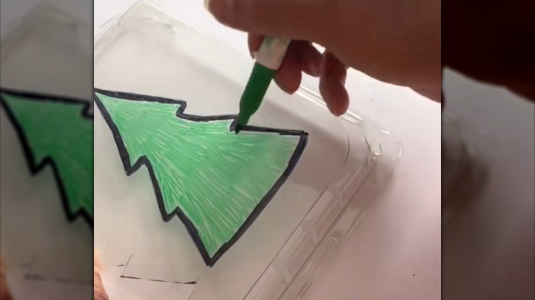 Woman coloring in Christmas tree design on clear fruit receptacle