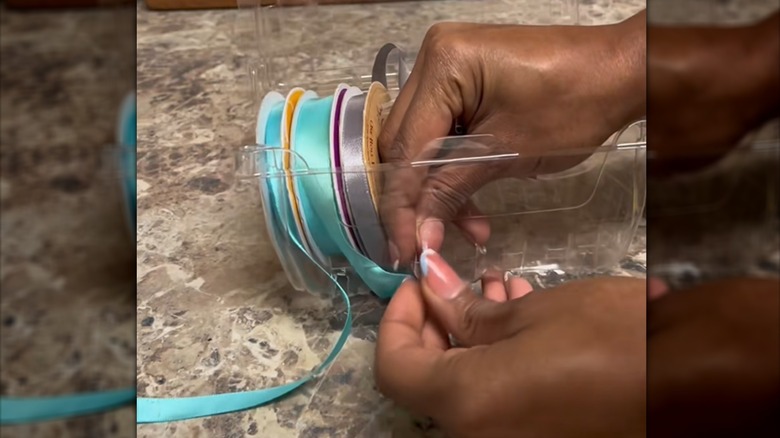 Woman threading satin ribbon spools through strawberry container holes