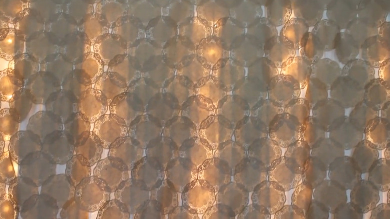 Doilies on a fabric backing with string lights behind them.