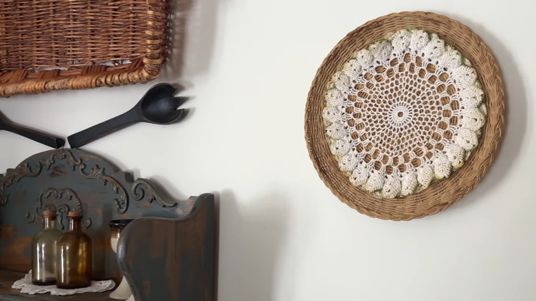 A doily attached to a wicker tray and hung on a wall