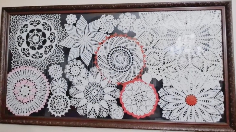 Various doilies arranged in a frame on a wall.