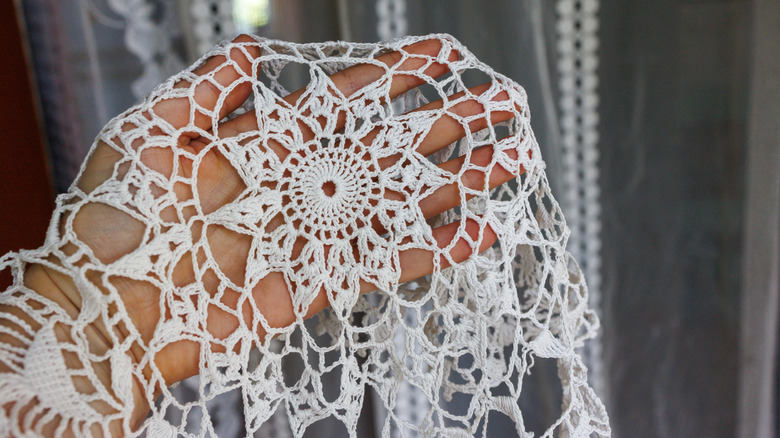 A person holding up a doily.
