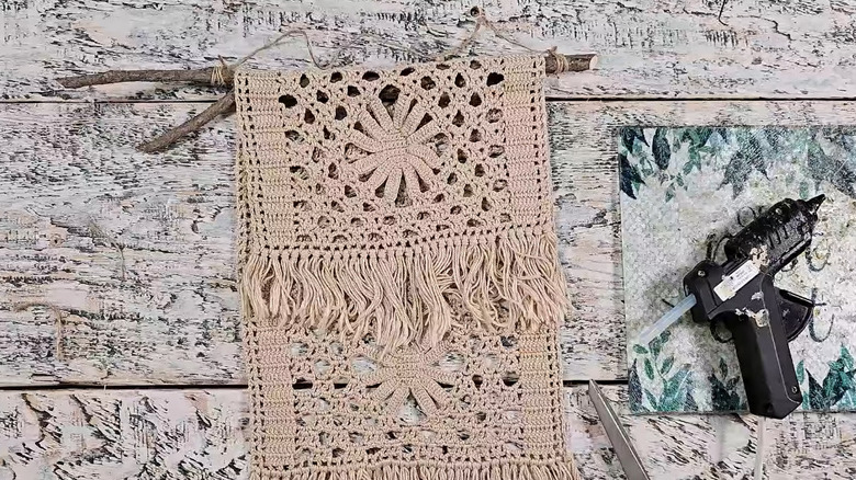 A doily tied to a stick to form a simple wall hanging.