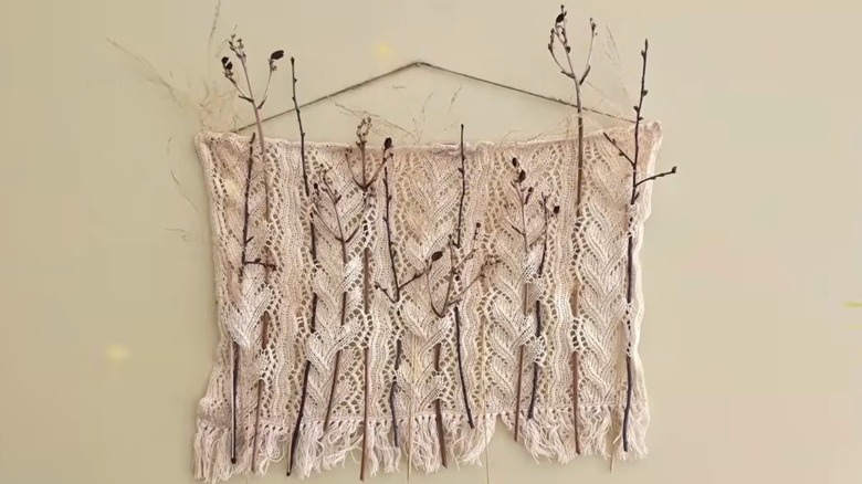 A doily with dried plants threaded through it.