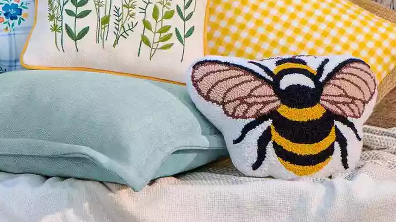 A variety of colorful spring motif pillows sits on a wooden bench