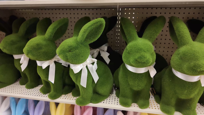 Several green flocked bunnies with white ribbons tied around their necks sit on a shelf at Hobby Lobby