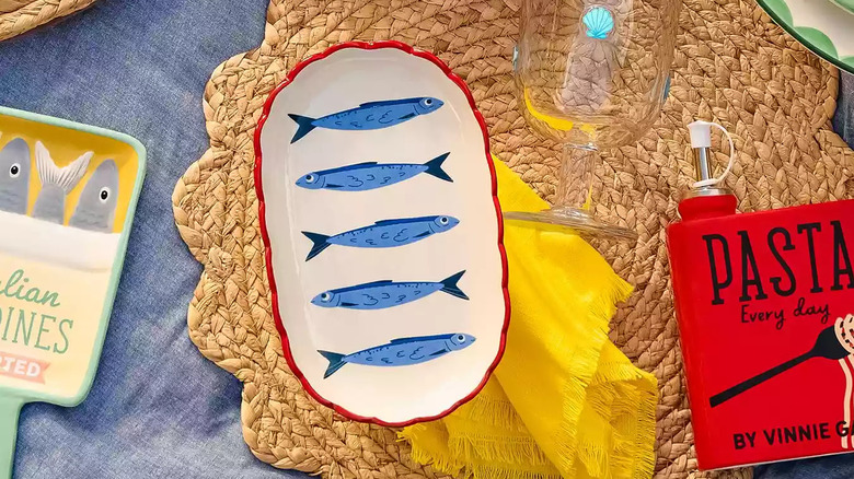 A small oval-shaped plate with a blue sardine print sits on a brown woven placemat