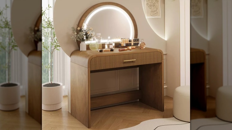 Small jars sit on a wood makeup table in front of a lighted mirror