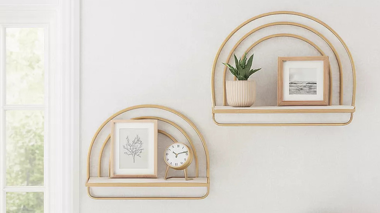 Two metal rainbow-shaped shelves hang on the wall next to a window