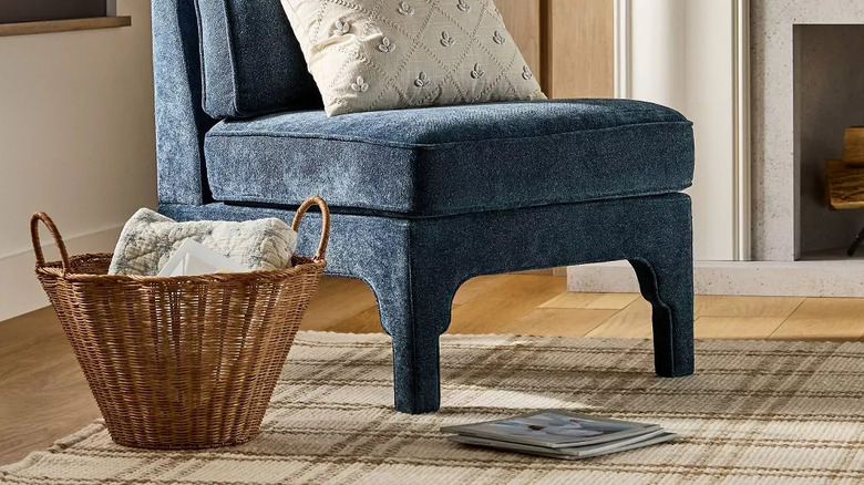 A large wicker basket sits next to a blue upholstered side chair