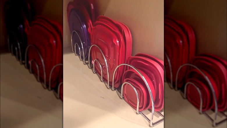 Assorted Tupperware lids tucked in napkin holders in clean kitchen cabinet