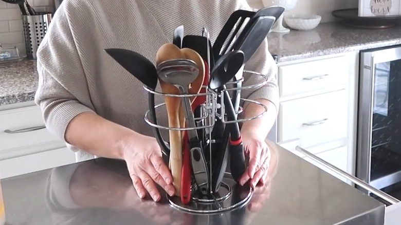 Woman showing off DIY wire utensil holder on metal kitchen counter
