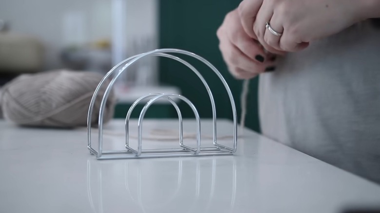 Wire napkin holder on table with gray yarn in the background