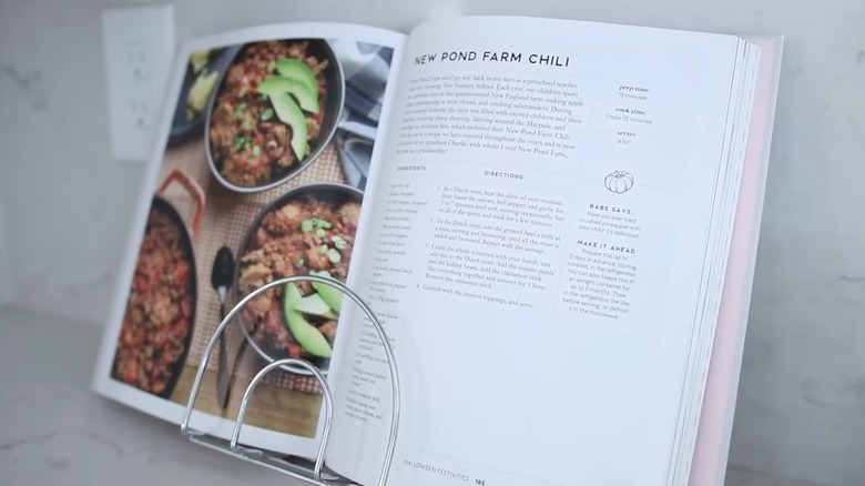 Halloween cookbook propped open on wire napkin holder on white kitchen countertop