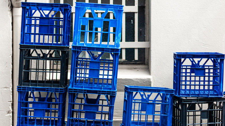Blue and black milk crates piled outside building gate